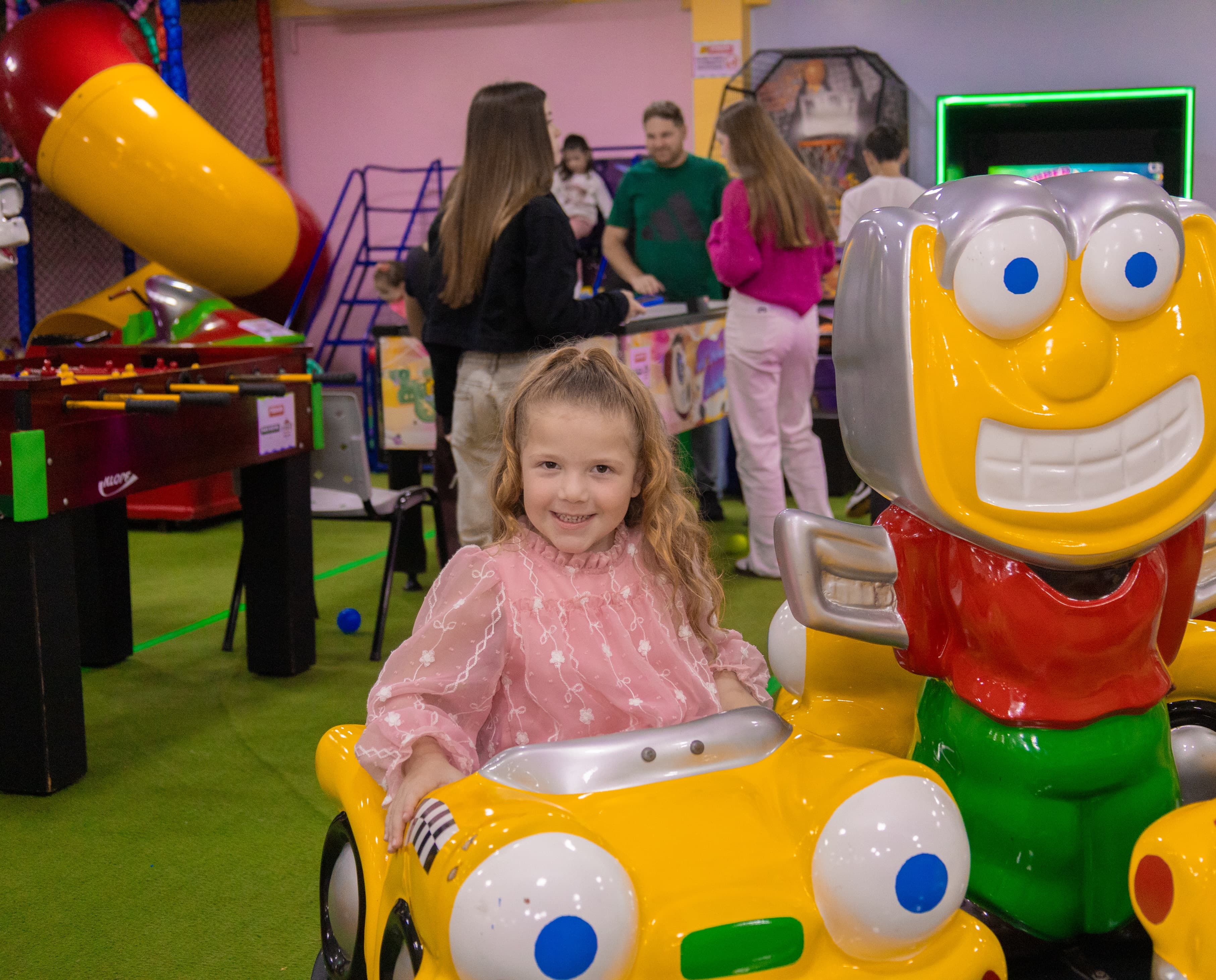 Menina sorrindo em um carrinho de brinquedo em uma festa